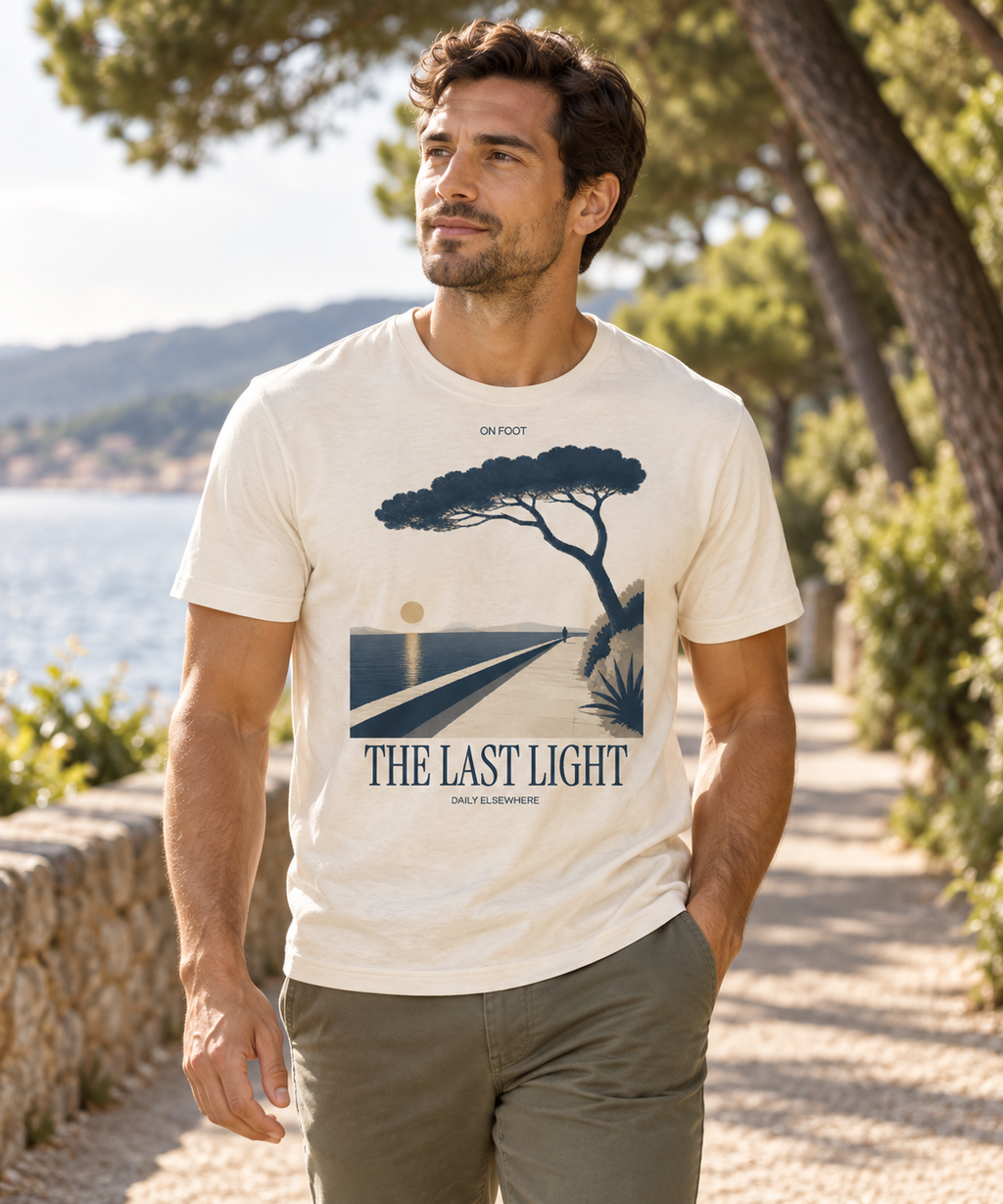 Male model wearing The Last Light Natural Raw T-shirt with dark coastal-path and tree artwork on the front.