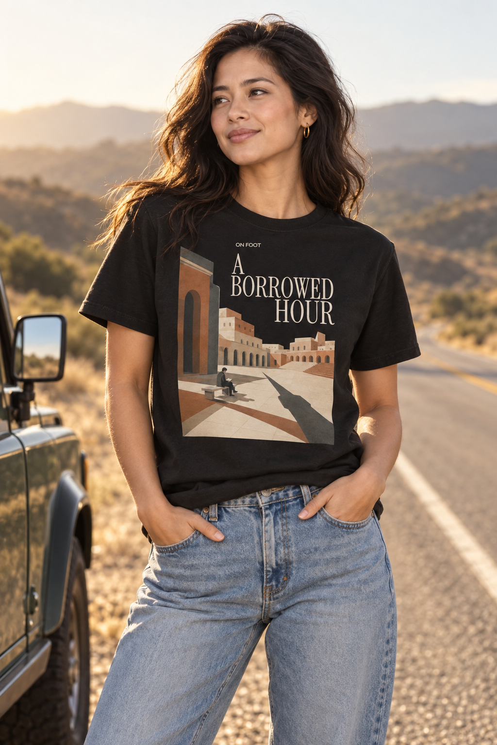 Female model wearing the A Borrowed Hour black T-shirt with light title lettering and courtyard artwork.