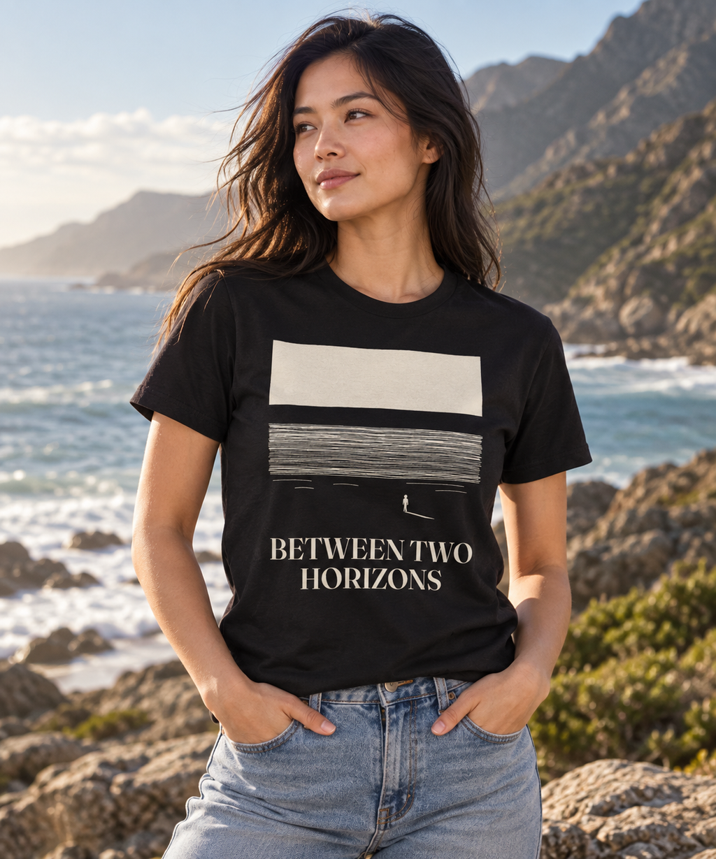 Between Two Horizons — Male model wearing a dark T-shirt with light front artwork. Daily Elsewhere.